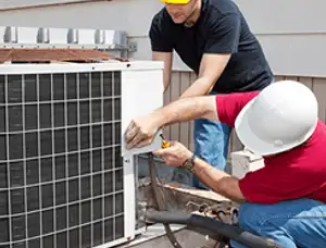 HVAC technicians repairing an outdoor AC unit on a rooftop in Chattanooga, TN