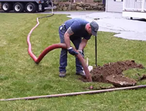 Septic pumping technician servicing a residential septic tank with a vacuum hose in Chattanooga, TN
