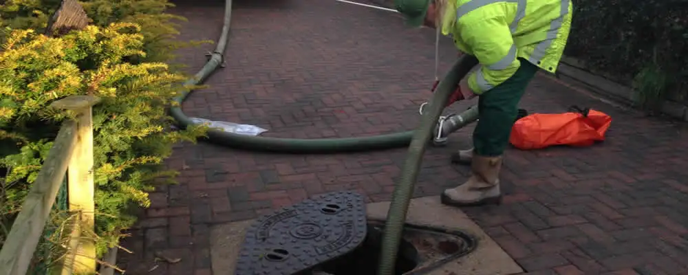 Septic tank cleaning technician servicing a septic tank with a vacuum hose in Chattanooga, TN