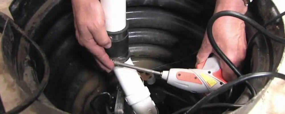 Sump pump installation technician connecting PVC discharge piping in Chattanooga, TN